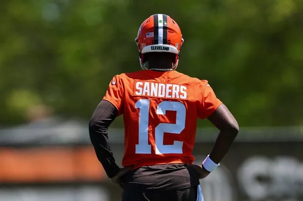 Shedeur Sanders holding his new Cleveland Browns jersey.
